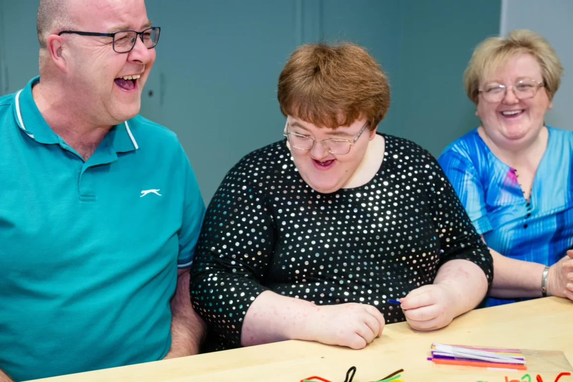 A man and two women sitting down laughing and smiling.
